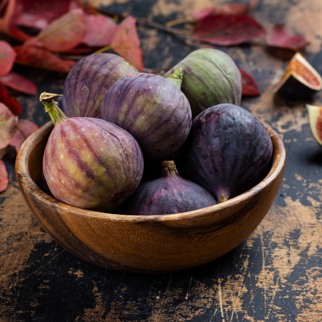 A wooden bowl filled with fresh, ripe Brown Turkey figs on a rustic table